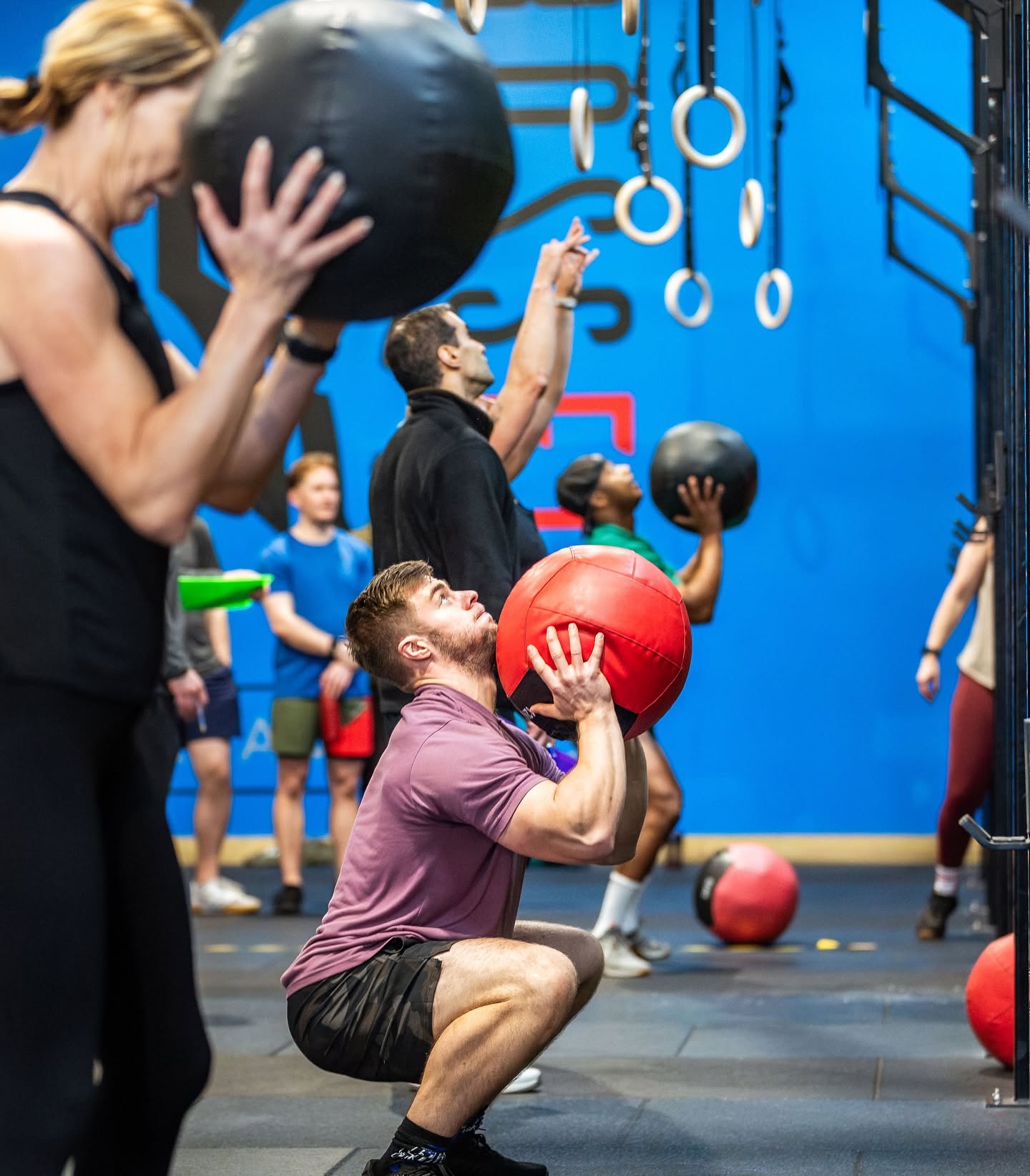 A full class hitting wall balls in unison beneath the blue spartan mural
