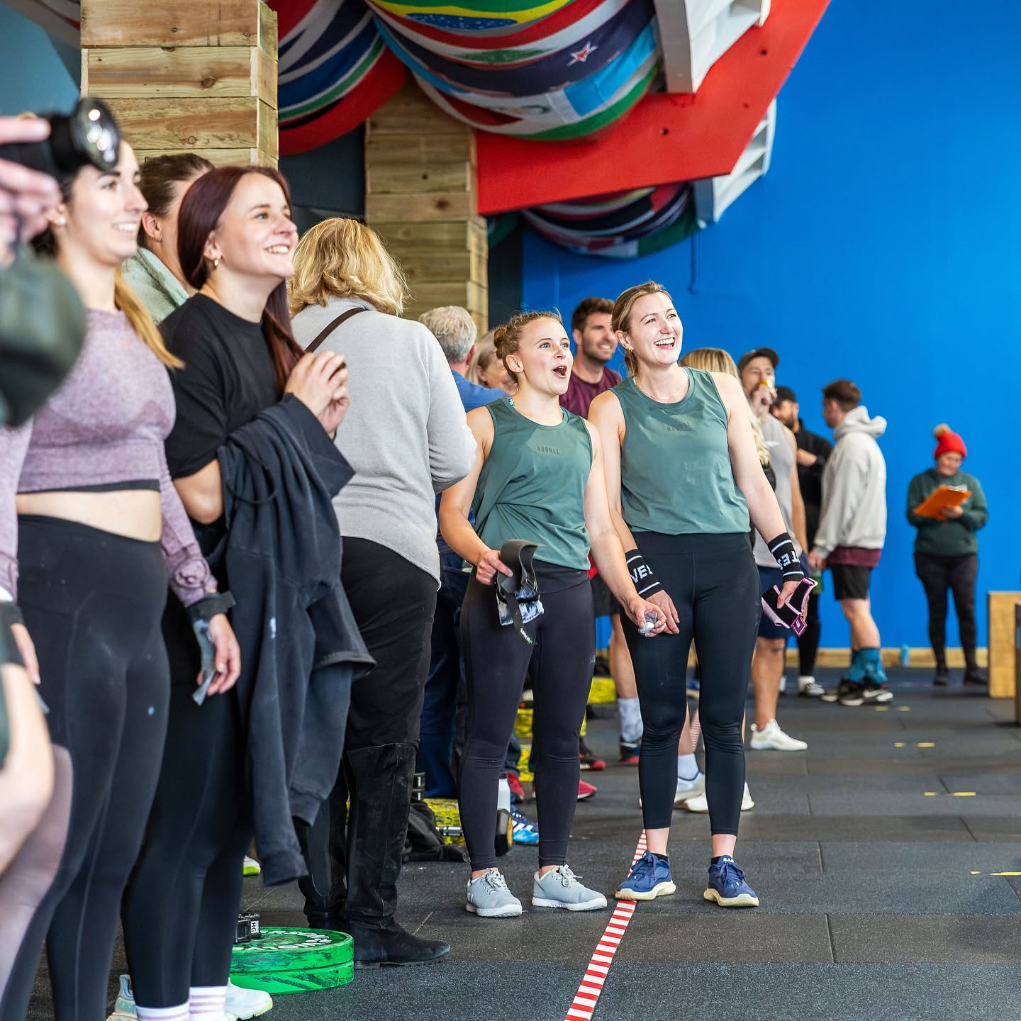 A crowd of members cheering under the international flags at CrossFit Leamington