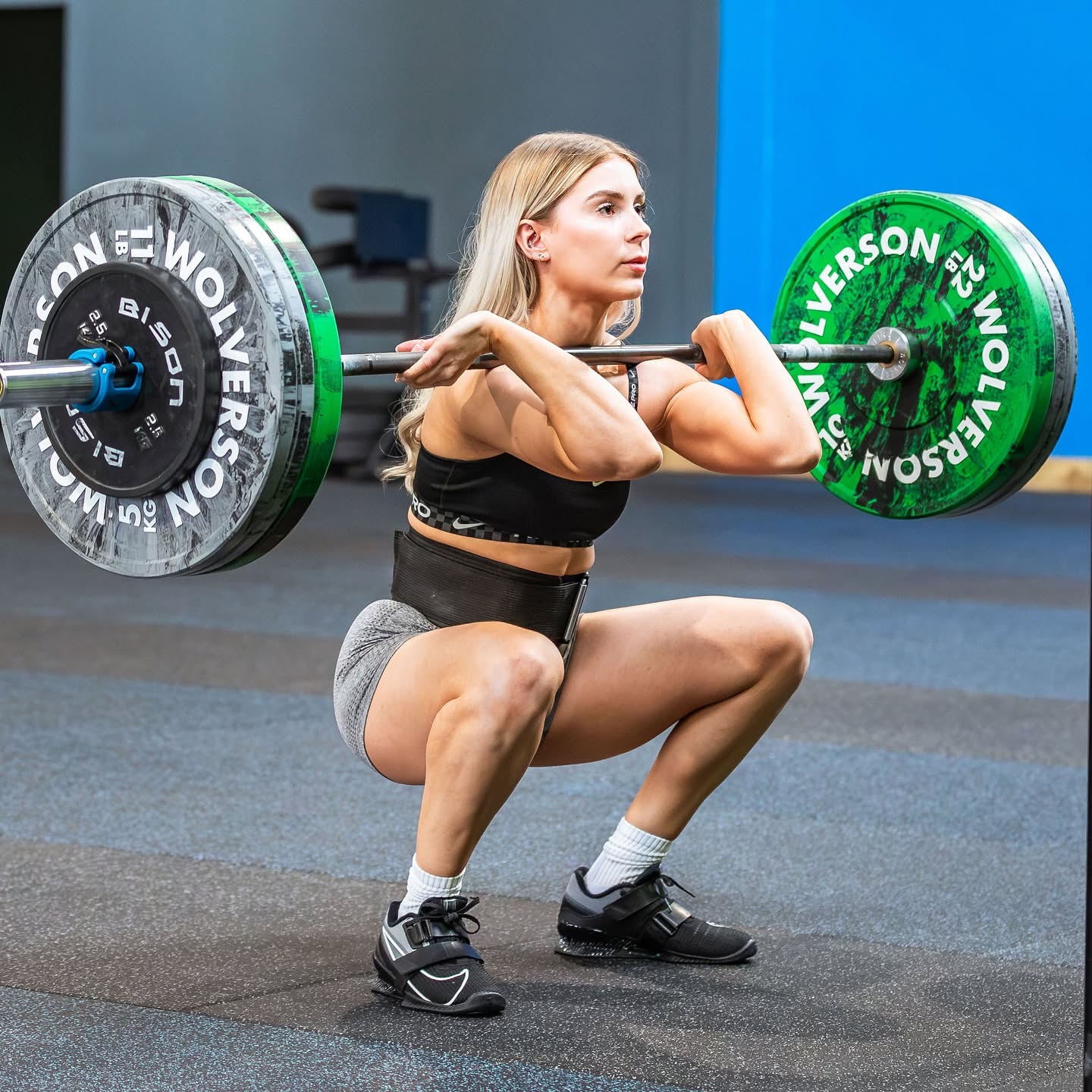 A member catching a barbell clean in a deep front squat